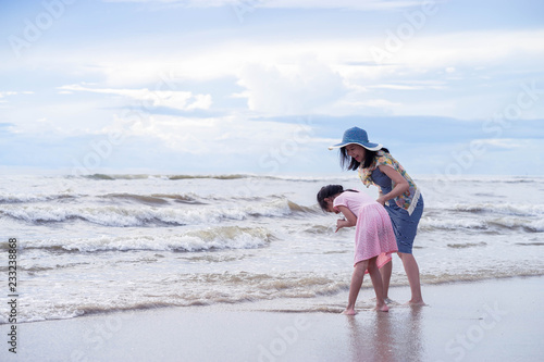 Asian Mother smiling with her daughter and hold one's hands on the beach