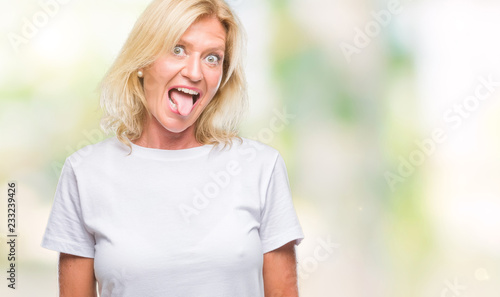 Middle age blonde woman over isolated background sticking tongue out happy with funny expression. Emotion concept. © Krakenimages.com