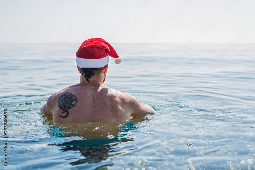 Man in Santa Claus hat on the beach, Christmas holidays.