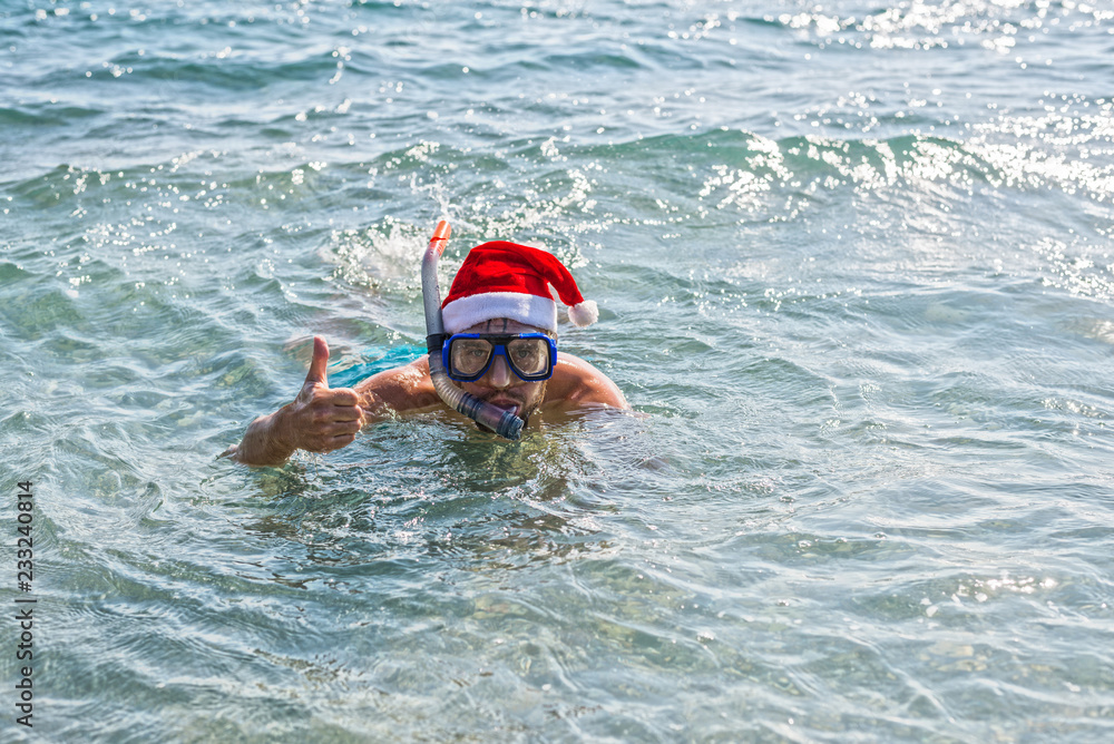 Man in a Santa Claus hat and diving mask, Christmas background with copy space.