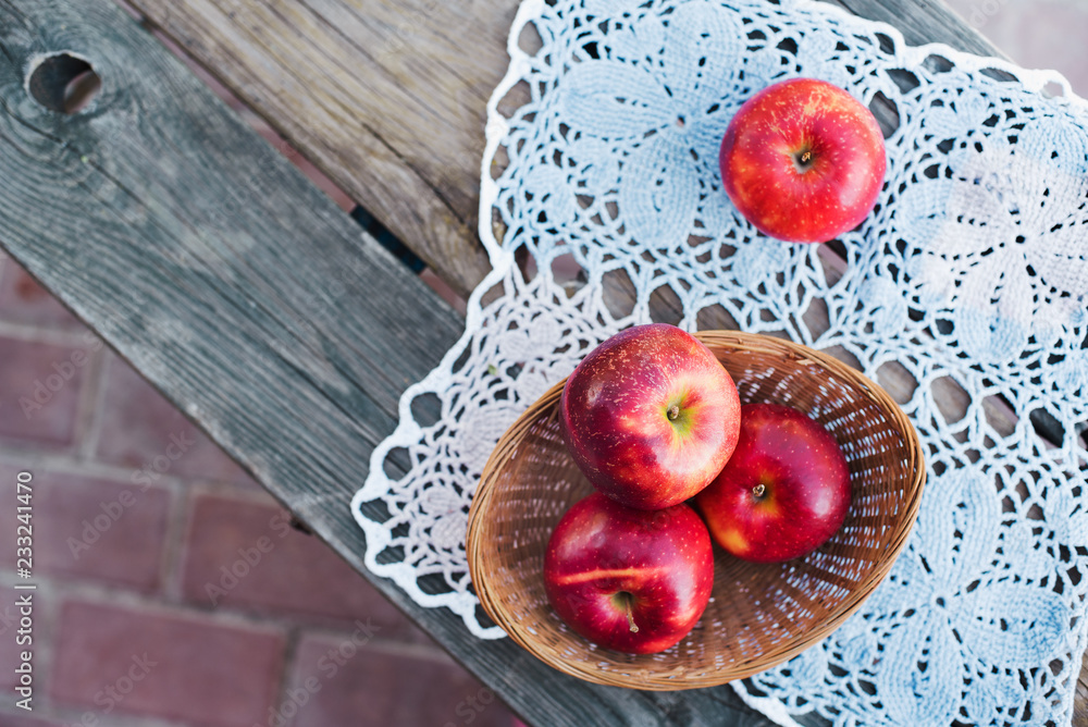 Autumn harvest. Red ripe apples in a wicker basket on a knitted napkin on a table in the garden on a Sunny day. Rustic style Autumn harvest. Red ripe apples in a wicker basket on a knitted napkin on a table in the garden on a Sunny day. Rustic style