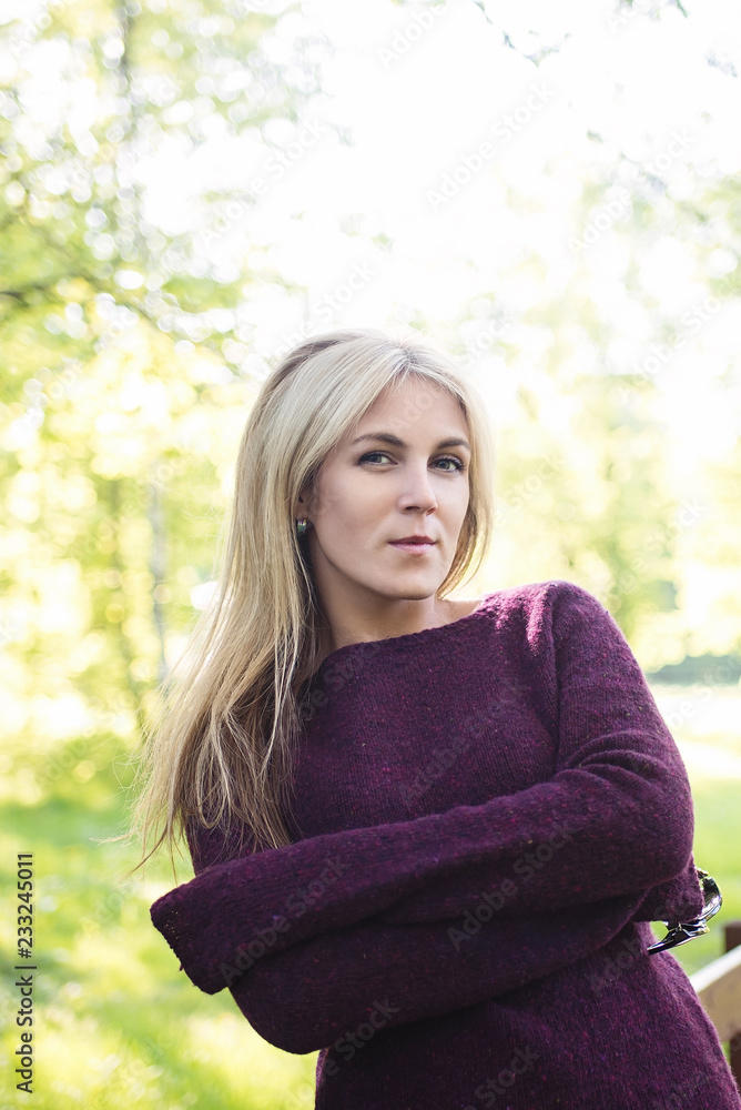 Obraz premium A walk in the Park. A girl with blond hair walks in the Park on a Sunny spring day. Blonde in the sun