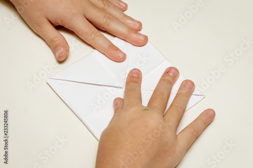 children's hands and a piece of paper for origami