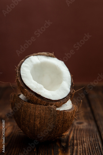 two ripe halves of the coconut shell on dark wooden table