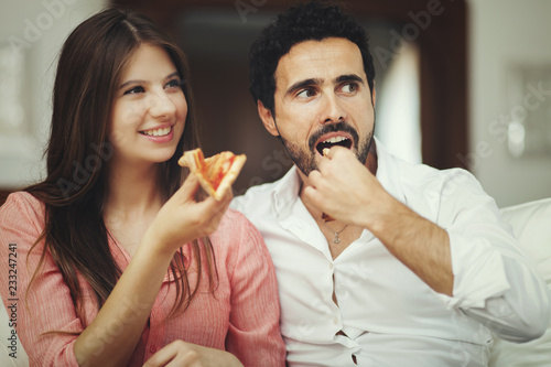 Couple eating pizza and watching TV