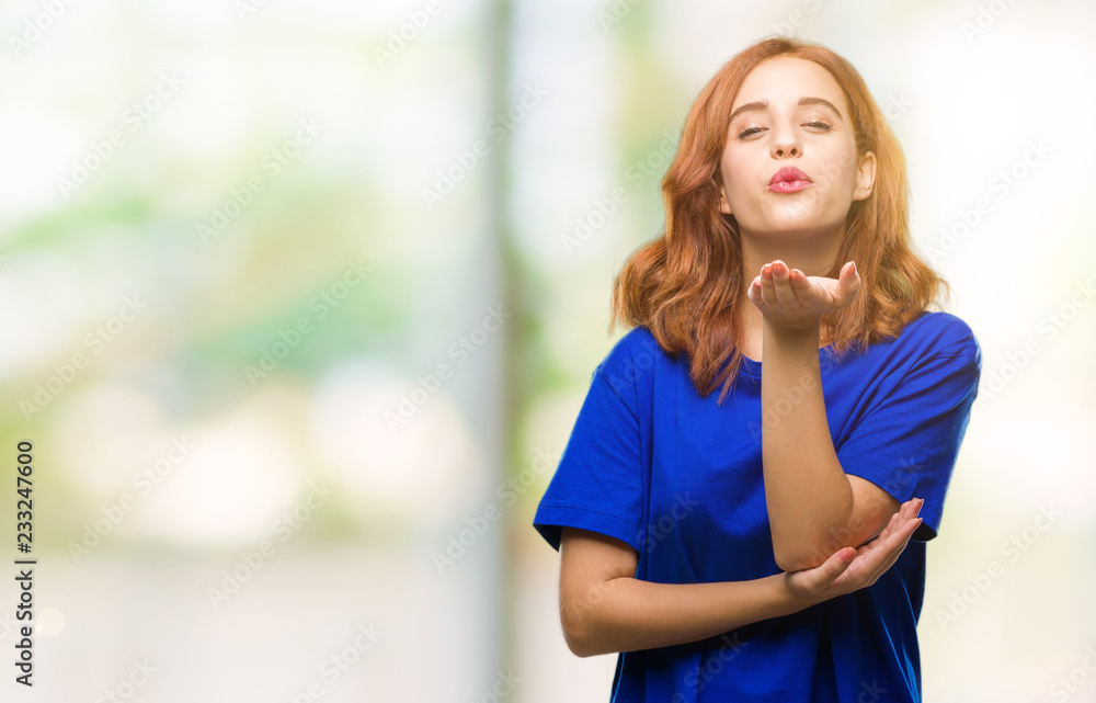 Young beautiful woman over isolated background looking at the camera blowing a kiss with hand on air being lovely and sexy. Love expression. Young beautiful woman over isolated background looking at the camera blowing a kiss with hand on air being lovely and sexy. Love expression.