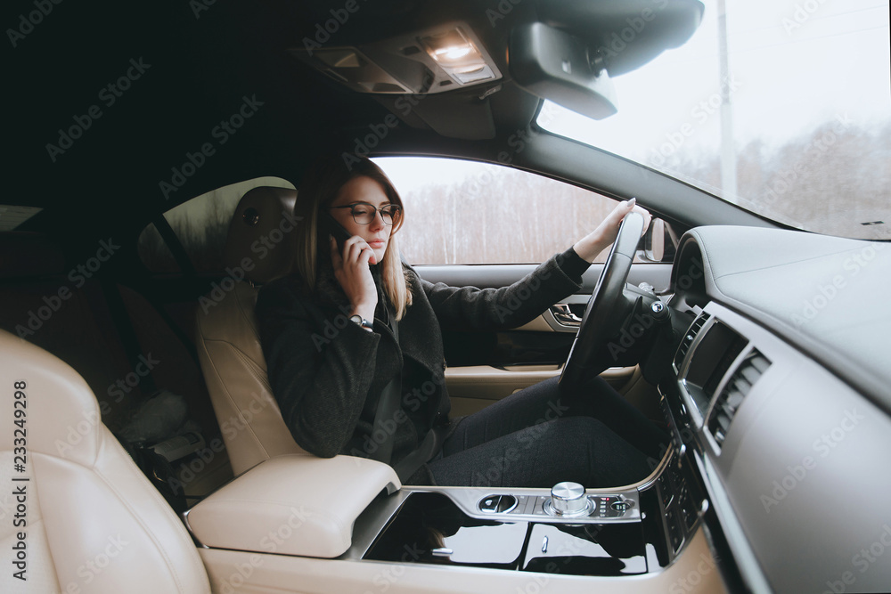 Young attractive blonde uses phone while sitting in car