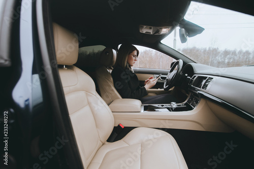 Young attractive blonde uses phone while sitting in car © Mirrorstudio
