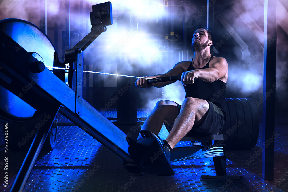 Bearded fit man using rowing machine at functional training