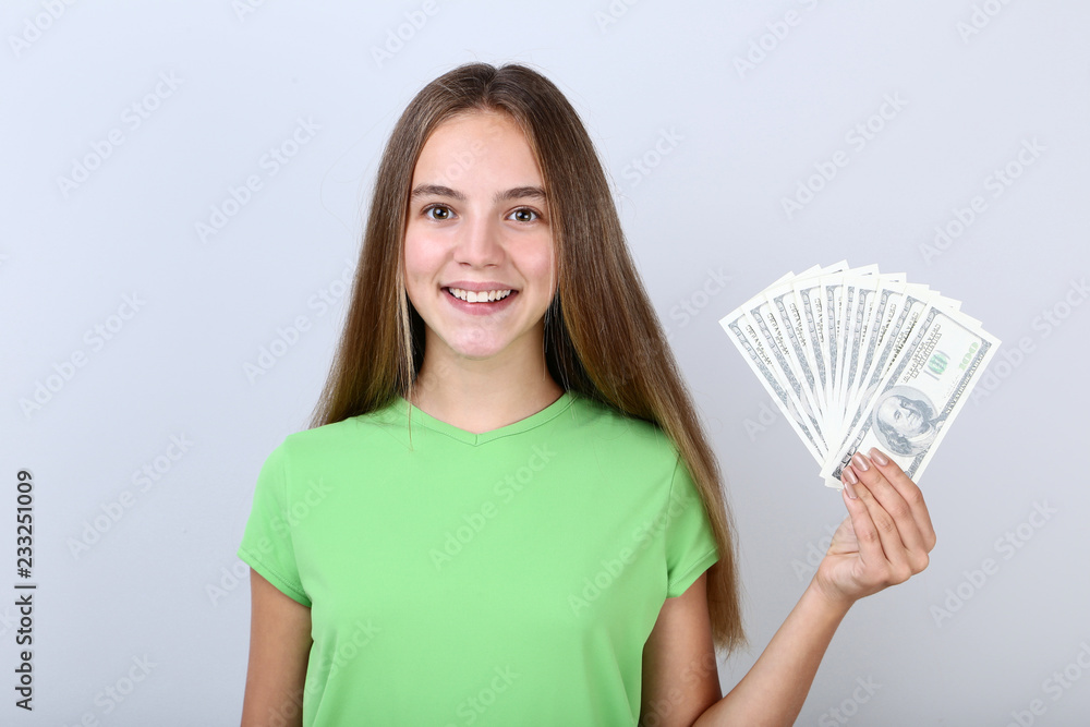 Young girl holding dollar banknotes on grey background Young girl holding dollar banknotes on grey background