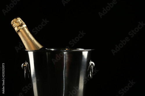Champagne bottle in bucket on black background