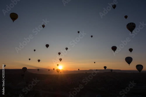 Hot air balloons in the sky during sunrise. Flying over the valley at Cappadocia, Anatolia, Turkey. Volcanic mountains in Goreme national park.