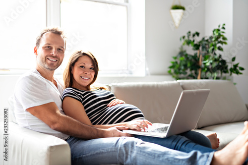 A Couple With Pregnant Woman Using Laptop Computer Together © Louis-Photo