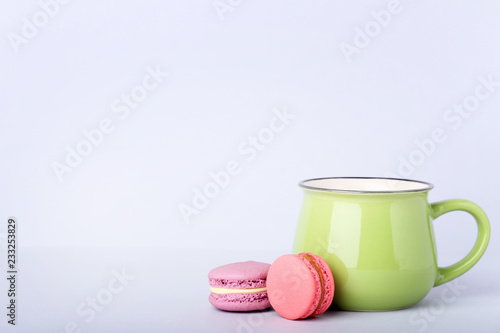 Green mug with macarons on grey background