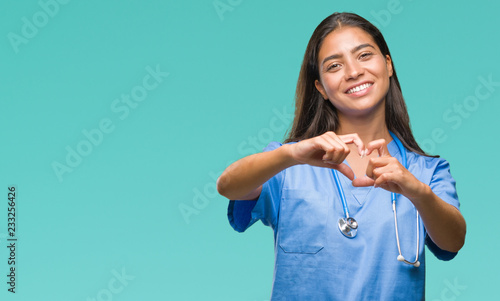 Young arab doctor surgeon woman over isolated background smiling in love showing heart symbol and shape with hands. Romantic concept. photo