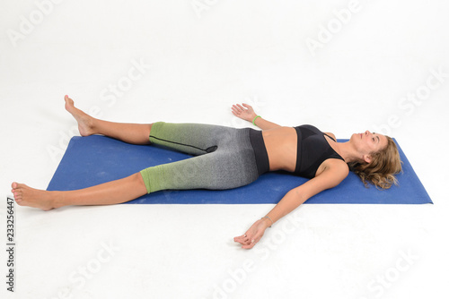 Beautiful young woman doing yoga on white background - shavasana photo