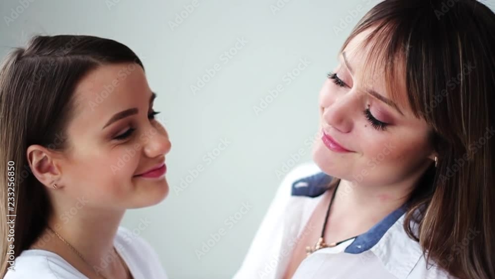 Portrait beautiful young mother with her daughter stand look at each other smile happy in studio white background attractive family female conversation cute girl close up slow motion Portrait beautiful young mother with her daughter stand look at each other smile happy in studio white background attractive family female conversation cute girl close up slow motion