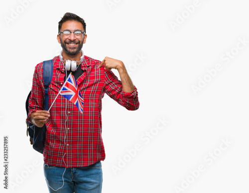 Adult hispanic student man holding passport of united kingdom over isolated background with surprise face pointing finger to himself