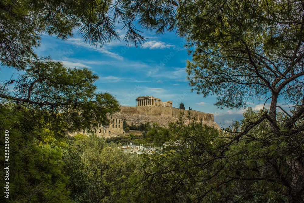 Great Greece and world heritage ancient temple Parthenon with scaffolding object in construction time, creative foreshortening through tree branches frame from park outdoor nature environment 