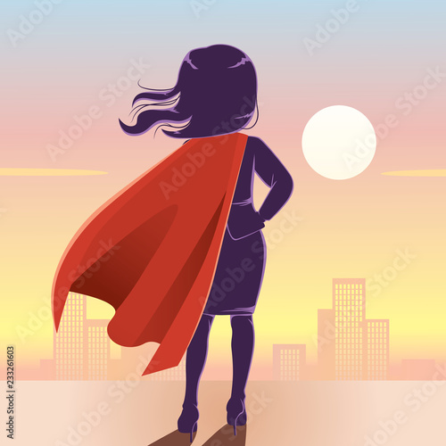 Back view of young powerful super businesswoman silhouette on top of city and sunset on background