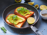 Grilled breads topping with avocado sliced and coriander in a pan on gray background for healthy  breakfast concept.