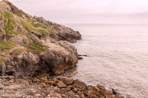 panorama of a rocky wall descending on the calm sea