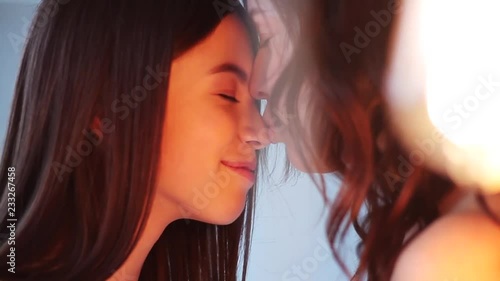 In yellow light mom and daughter hugging showing love and affection look each other in white studio smile happy family mother together cute pretty teenager portrait close up slow motion