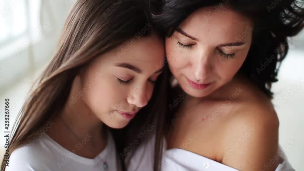 Beautiful closed eyes mom and daughter hugging showing love and affection in white studio smile happy family mother together cute pretty teenager portrait close up slow motion Beautiful closed eyes mom and daughter hugging showing love and affection in white studio smile happy family mother together cute pretty teenager portrait close up slow motion
