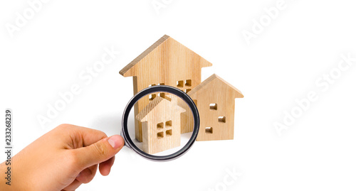 Magnifying glass is looking at the City of wooden houses on a white background. The concept of urban planning, infrastructure projects. Buying and selling real estate, building new buildings.