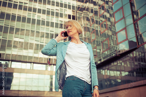 Beautiful business woman talking on a cell phone in front of the office building