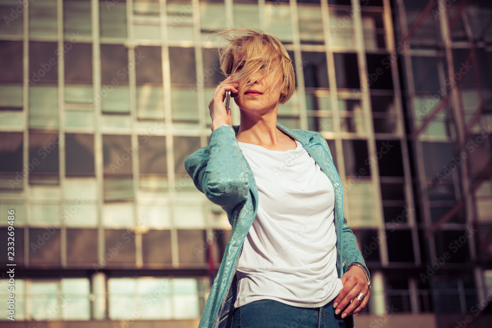 Fototapeta premium Beautiful business woman talking on a cell phone in front of the office building