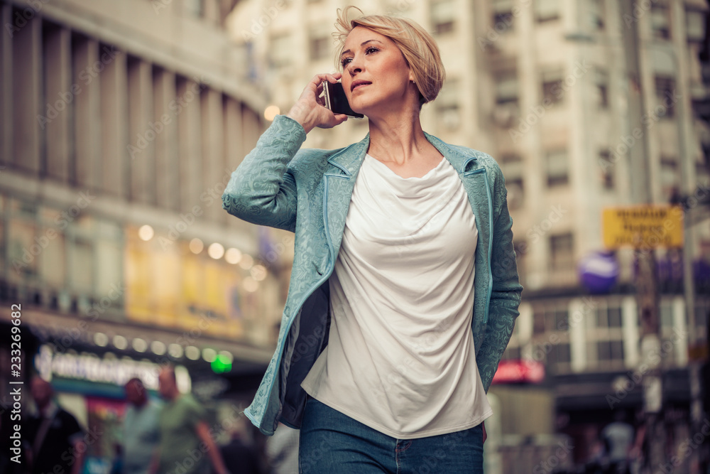 Confident mid-age woman talking on a cell phone in the street Confident mid-age woman talking on a cell phone in the street