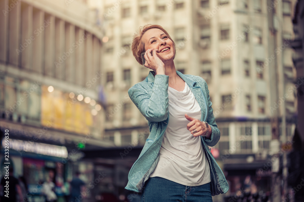 Confident mid-age woman talking on a cell phone in the street