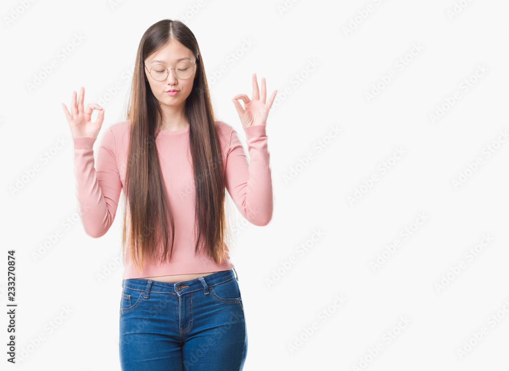 Young Chinese woman over isolated background wearing glasses relax and smiling with eyes closed doing meditation gesture with fingers. Yoga concept.