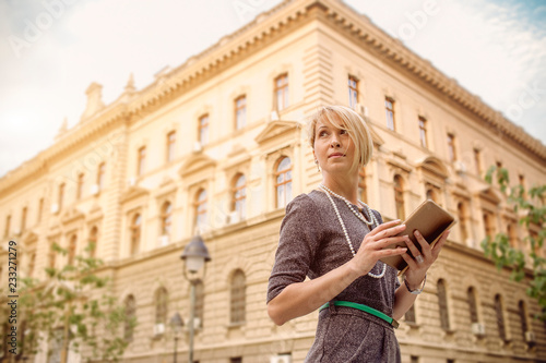 Elegant business woman uses a tablet in front of a office building