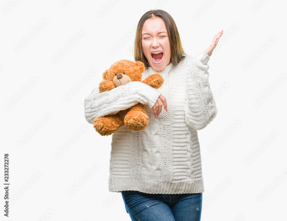 Young caucasian woman holding teddy bear over isolated background very happy and excited, winner expression celebrating victory screaming with big smile and raised hands Young caucasian woman holding teddy bear over isolated background very happy and excited, winner expression celebrating victory screaming with big smile and raised hands
