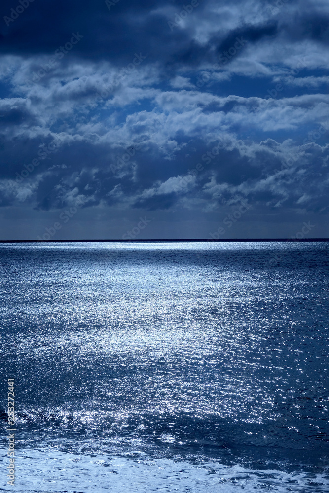 seascape of deep blue sea and sky lit by moonlight