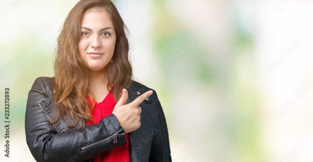 Beautiful plus size young woman wearing a fashion leather jacket over isolated background Pointing with hand finger to the side showing advertisement, serious and calm face Beautiful plus size young woman wearing a fashion leather jacket over isolated background Pointing with hand finger to the side showing advertisement, serious and calm face
