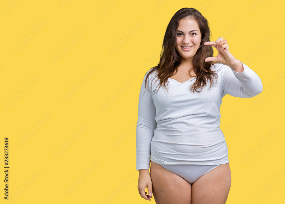Beautiful plus size young overwight woman wearing white underwear over isolated background smiling and confident gesturing with hand doing size sign with fingers Beautiful plus size young overwight woman wearing white underwear over isolated background smiling and confident gesturing with hand doing size sign with fingers