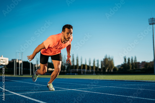 Young athlete man starting to run in a start position in a race. Start stride