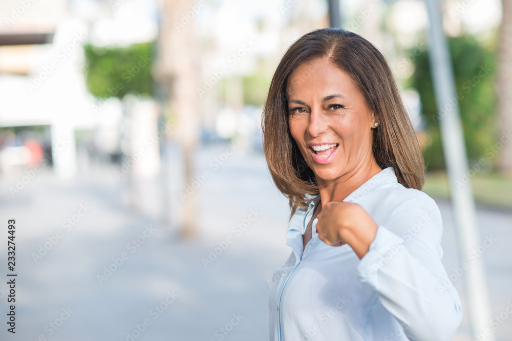 Beautiful middle age hispanic woman at the city street on a sunny day with surprise face pointing finger to himself Beautiful middle age hispanic woman at the city street on a sunny day with surprise face pointing finger to himself