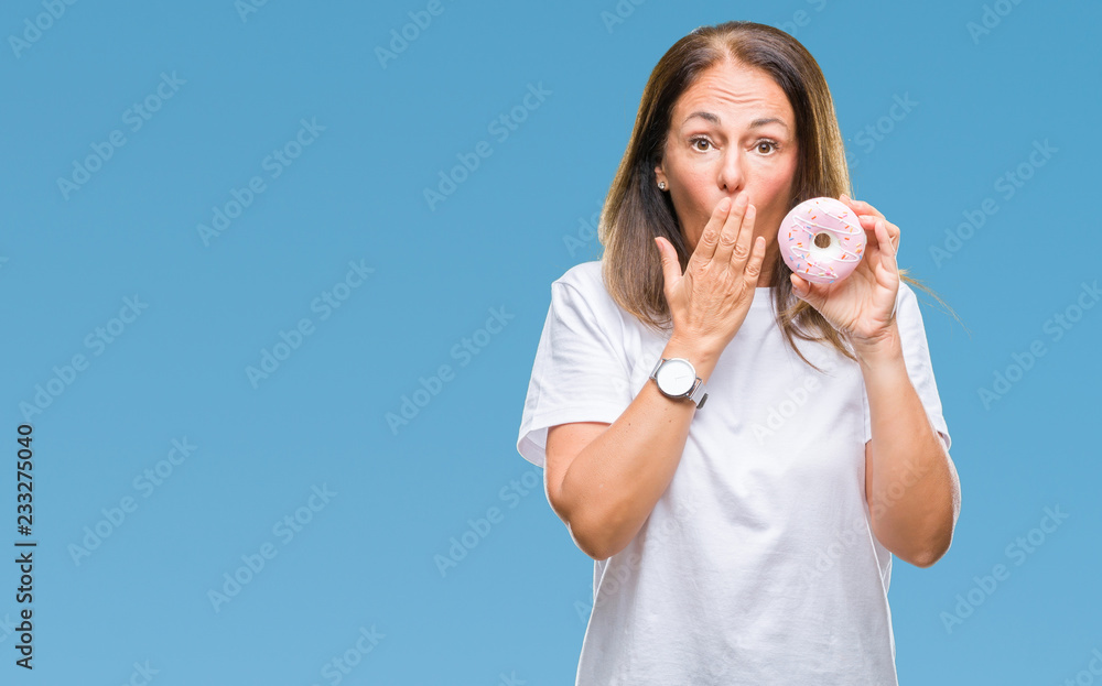 Middle age hispanic woman eating pink donut over isolated background cover mouth with hand shocked with shame for mistake, expression of fear, scared in silence, secret concept Middle age hispanic woman eating pink donut over isolated background cover mouth with hand shocked with shame for mistake, expression of fear, scared in silence, secret concept