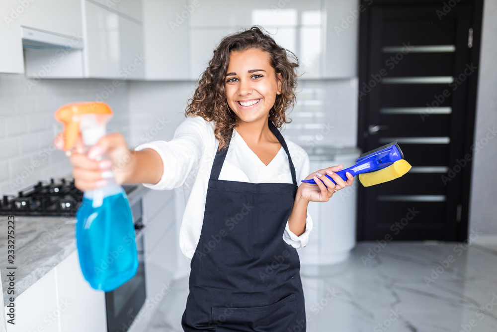 Young latin woman with bottle of detergent in kitchen Young latin woman with bottle of detergent in kitchen