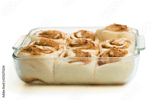 Raw cinnamon buns in clear glass baking form isolated on white