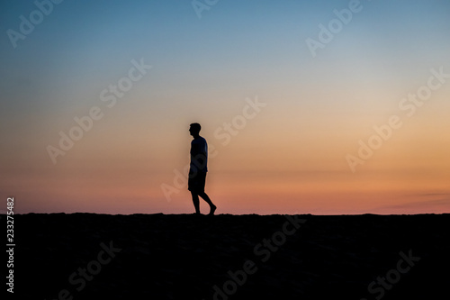 silhouette of man running on the beach at sunset © JKeiser