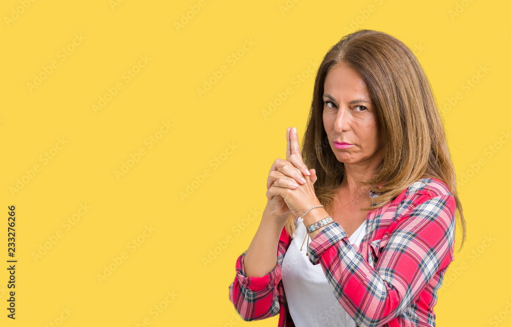 Beautiful middle age woman wearing over isolated background Holding symbolic gun with hand gesture, playing killing shooting weapons, angry face Beautiful middle age woman wearing over isolated background Holding symbolic gun with hand gesture, playing killing shooting weapons, angry face