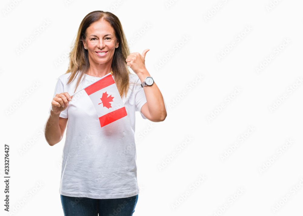 Middle age hispanic woman holding flag of Canada over isolated background pointing and showing with thumb up to the side with happy face smiling Middle age hispanic woman holding flag of Canada over isolated background pointing and showing with thumb up to the side with happy face smiling