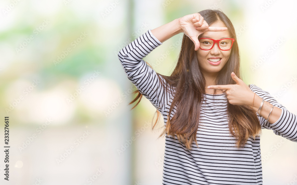 Young asian woman wearing glasses over isolated background smiling making frame with hands and fingers with happy face. Creativity and photography concept.