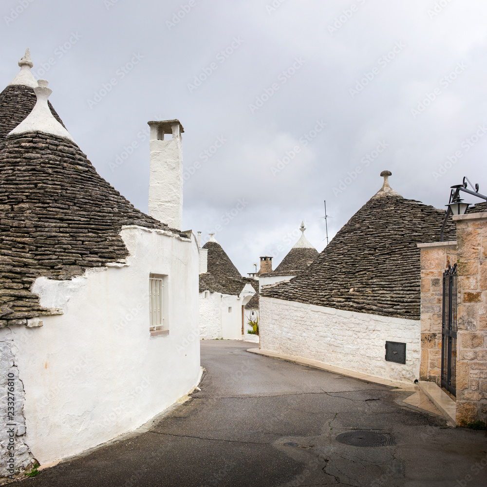 white houses on curved street with gray clouds in Alberobello in Puglia in Italy