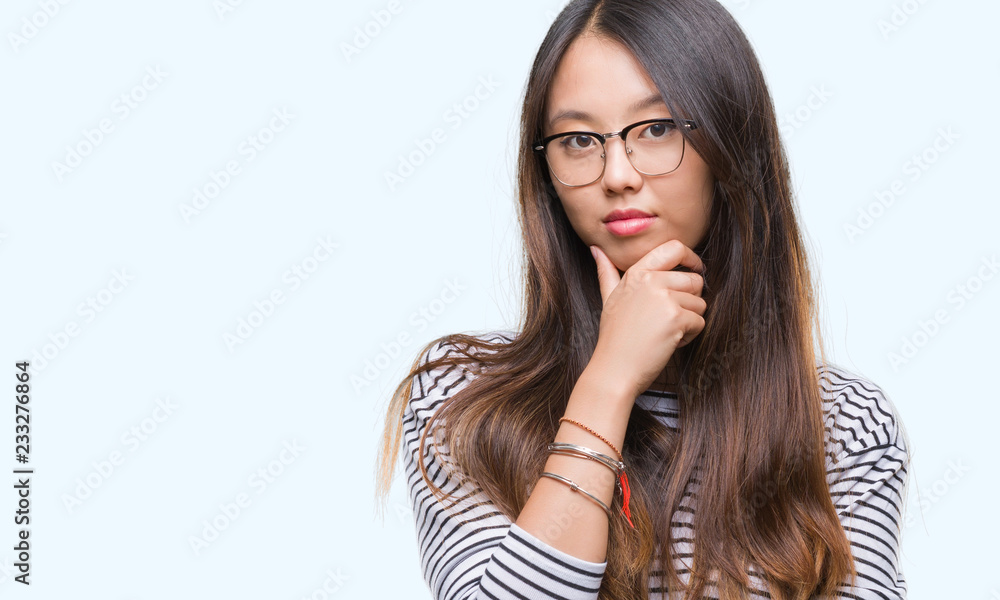 Young asian woman wearing glasses over isolated background looking confident at the camera with smile with crossed arms and hand raised on chin. Thinking positive. Young asian woman wearing glasses over isolated background looking confident at the camera with smile with crossed arms and hand raised on chin. Thinking positive.